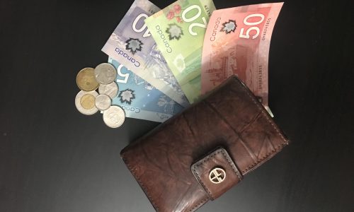 purse with Canadian bills and coins on a black surface